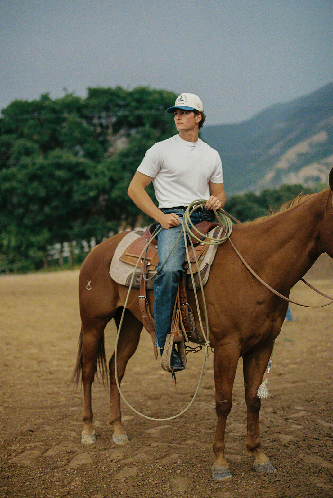 Rider sitting on horseback with rope in hand in an arena